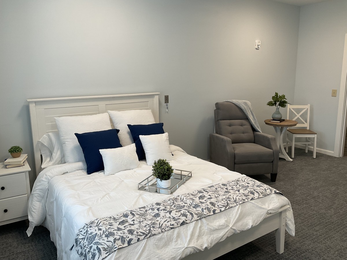 A modern and cozy bedroom with a neatly made bed, decorative pillows, and a small plant on a tray.