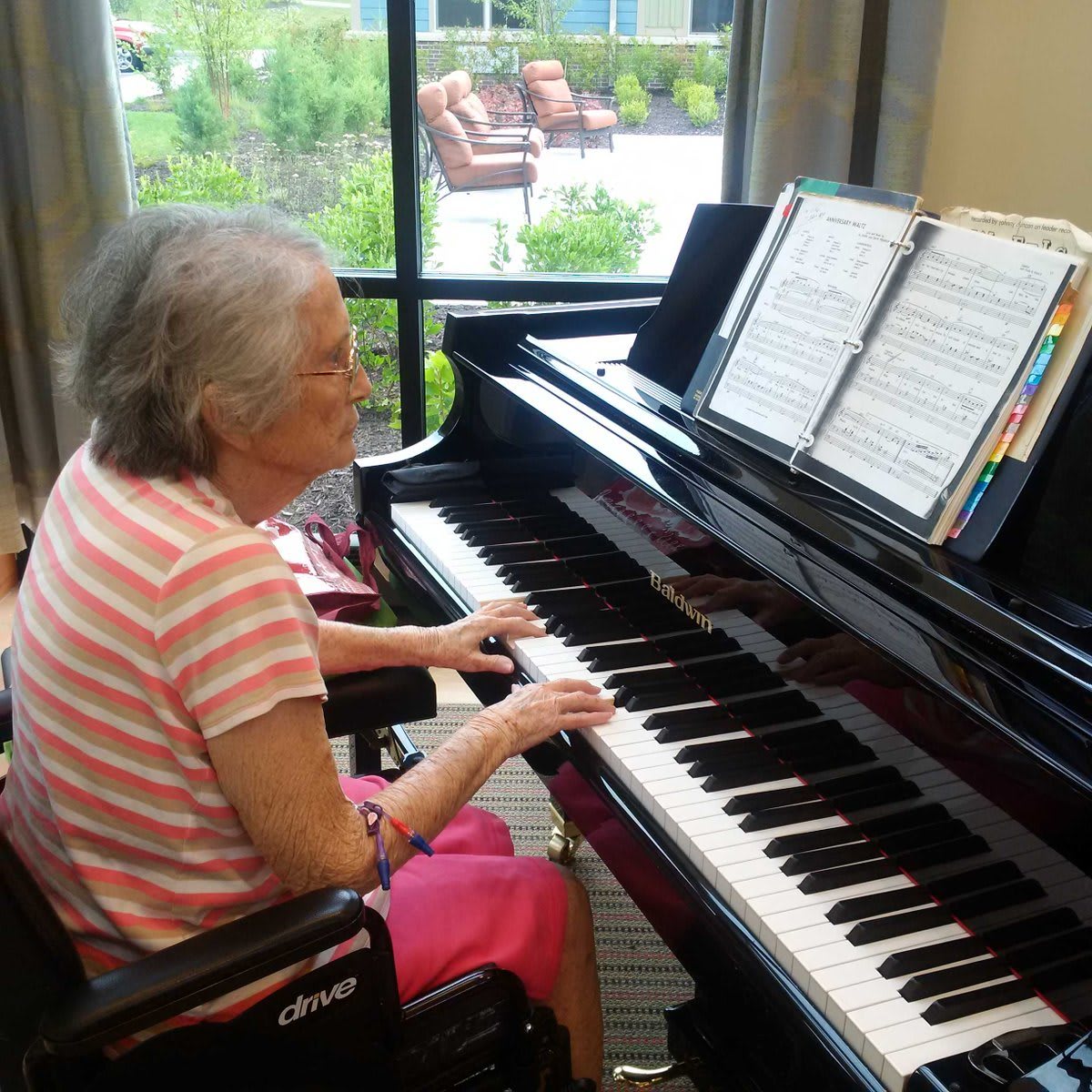 A senior person playing the piano indoors.