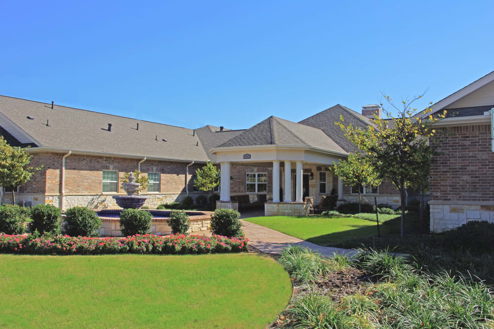 A suburban house with a well-maintained garden and front porch under a clear blue sky.