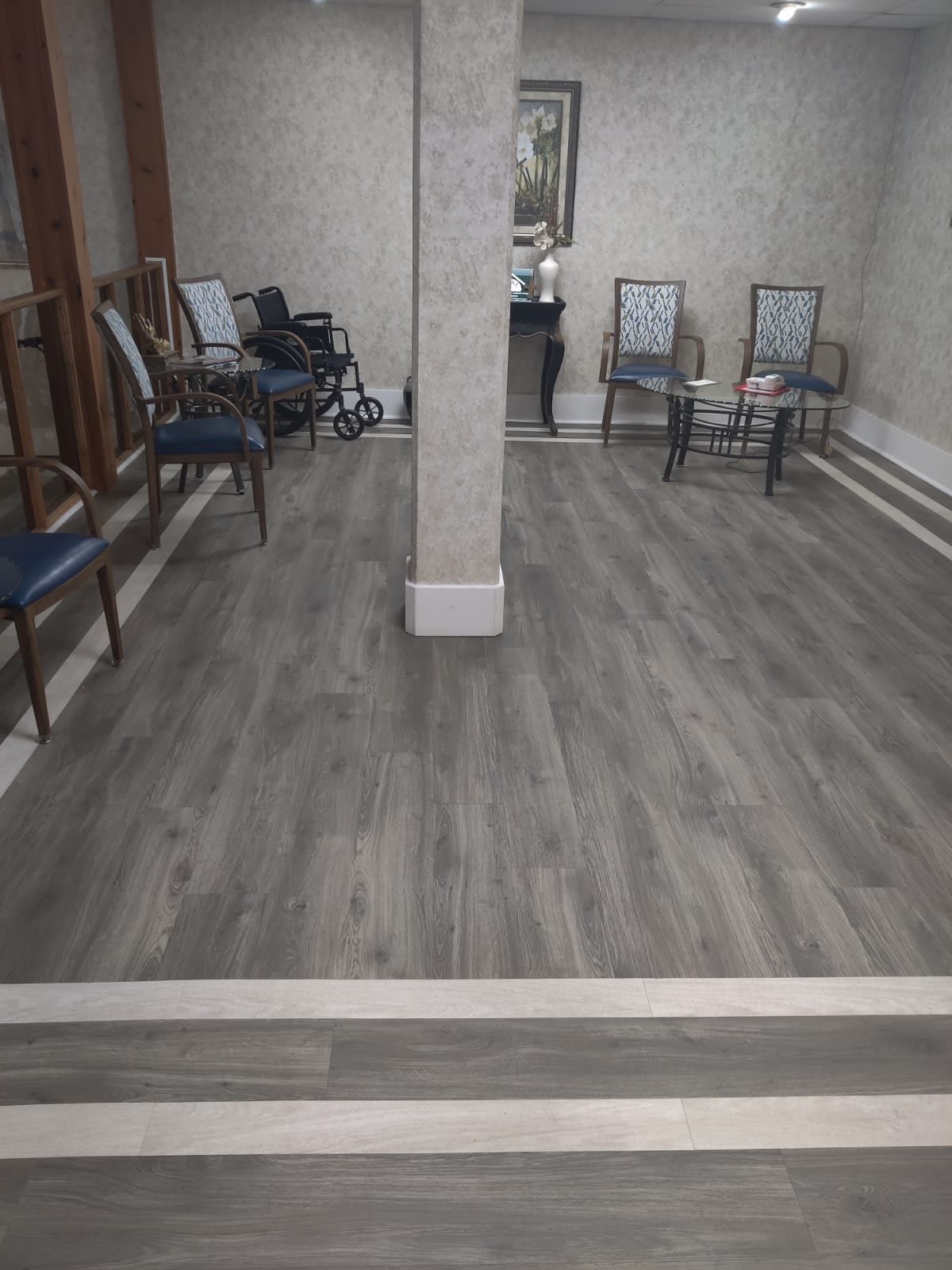 A spacious waiting area with chairs arranged along the walls and light-colored flooring.