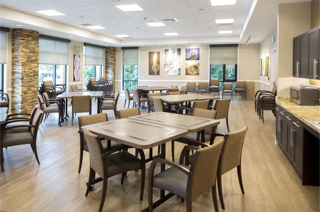 A modern dining area with neatly arranged tables and chairs, featuring bright lighting and a spacious layout.