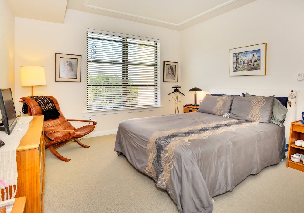 A cozy bedroom with a double bed, artwork on the walls, and a comfortable chair by the window.