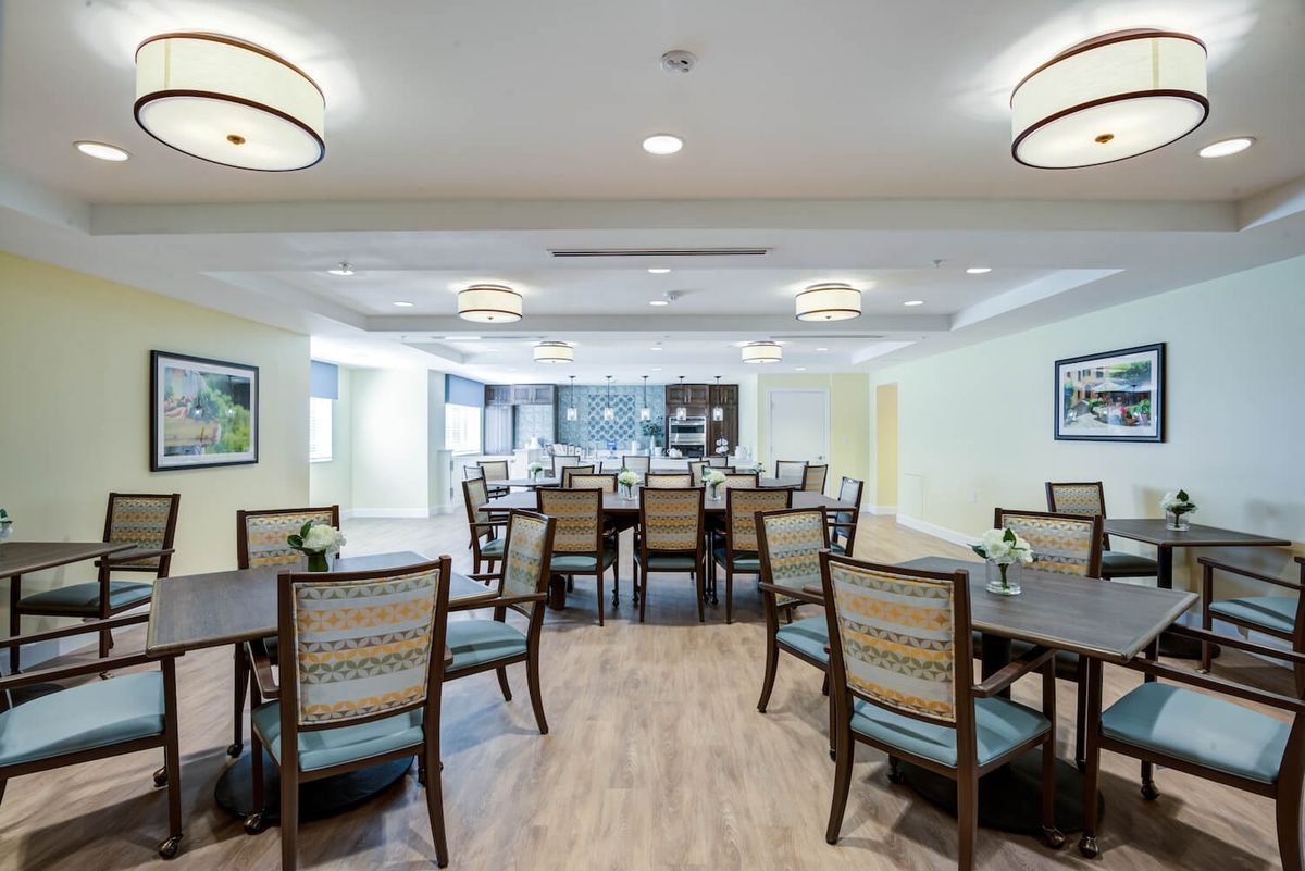 A spacious dining area with neatly arranged tables and chairs, illuminated by modern ceiling lights.