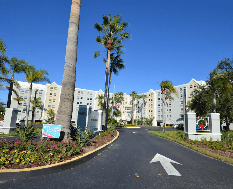 Entrance to a hotel with palm trees and clear blue sky.
