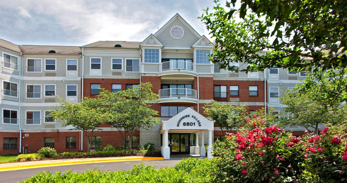 A residential apartment building with a landscaped entrance and greenery.