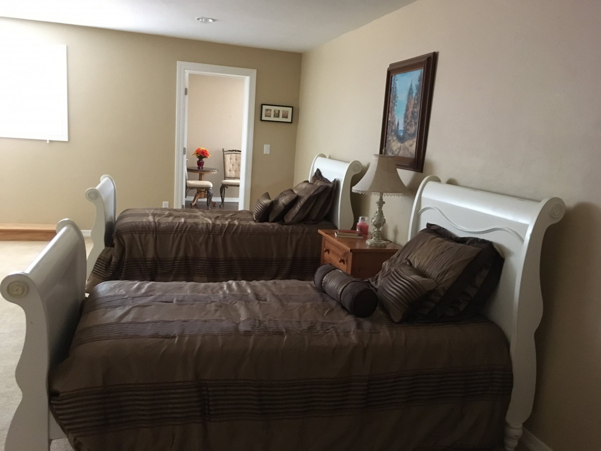 A cozy bedroom featuring two twin beds with brown bedding and decorative pillows, enhanced by a painting and a lamp.
