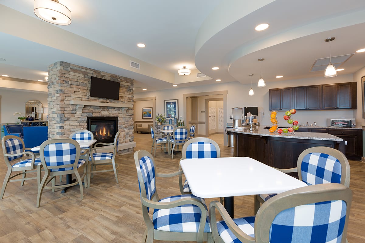 A cozy dining area with checkered chairs and a stone fireplace.