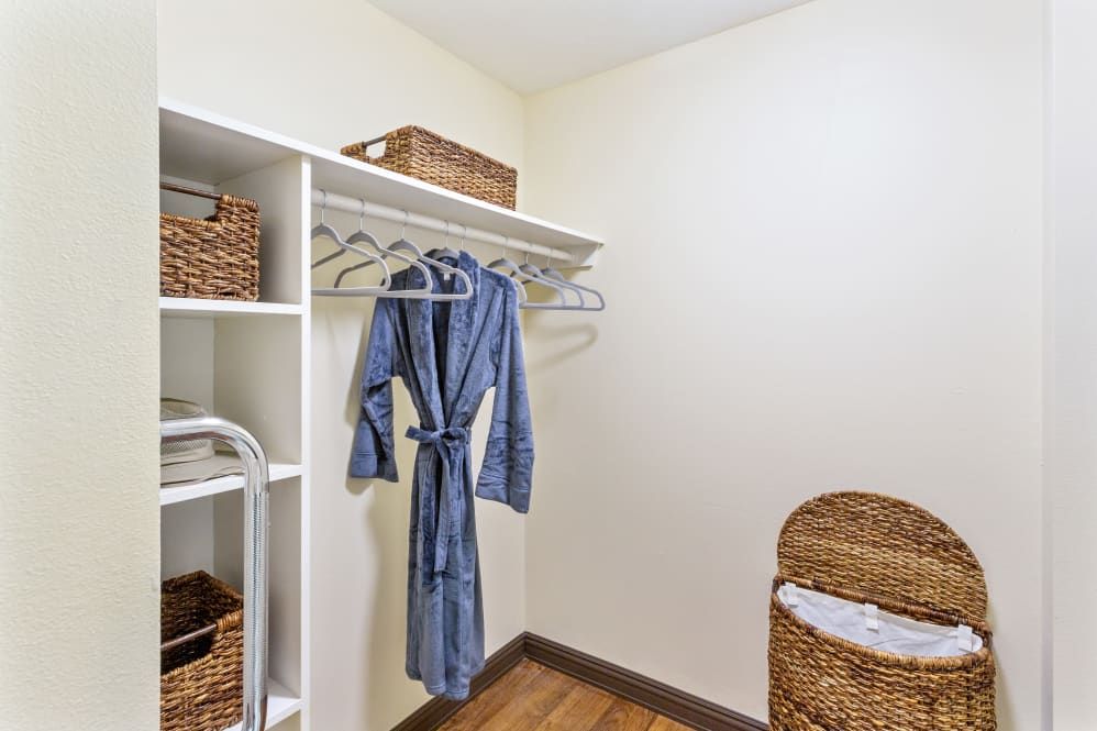A neatly organized closet with a robe hanging and storage baskets on the shelves.