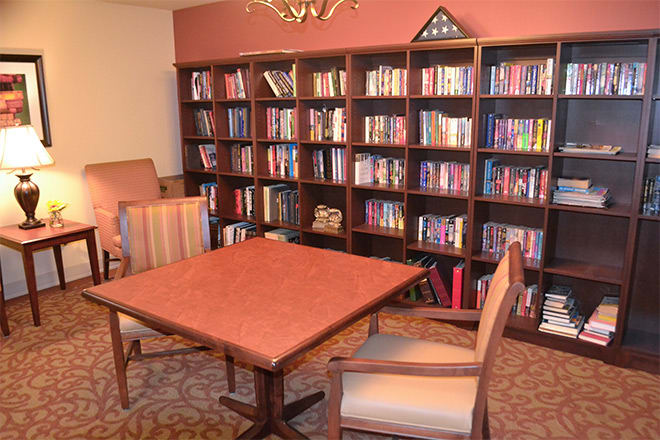 A cozy library reading room with bookshelves, a table, and chairs.