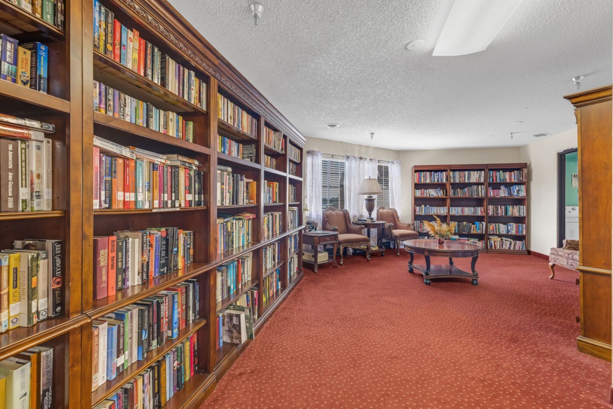 A cozy library room with bookshelves filled with books and a comfortable reading area.