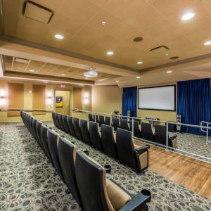 An empty theater with rows of seats facing a large screen, ready for a presentation or screening.
