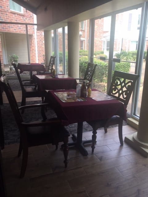 Cozy restaurant interior with tables and chairs by the window, offering a pleasant daytime view.