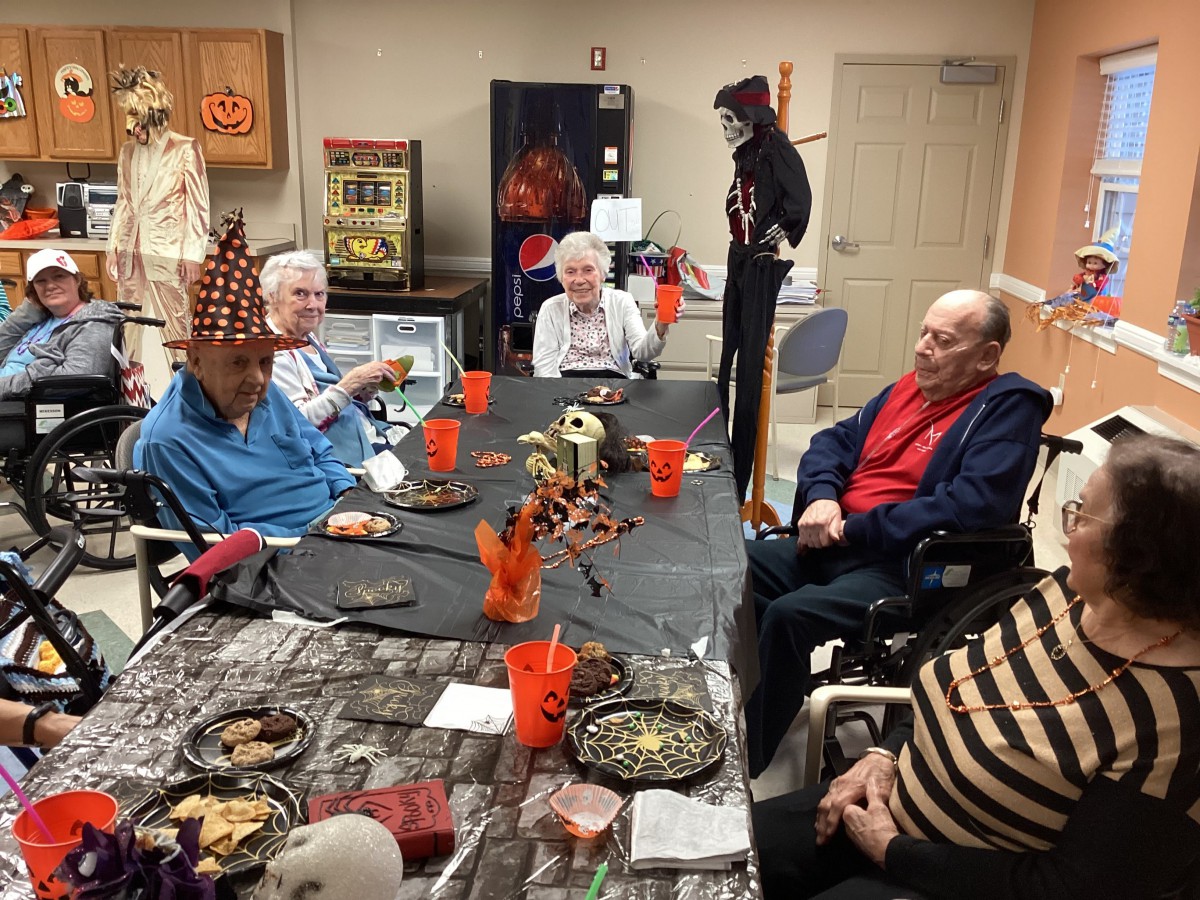 A group of seniors enjoying a Halloween party with costumes and decorations.