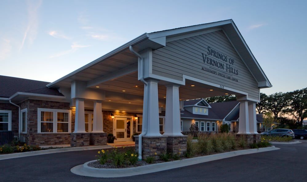 A well-lit building entrance with columns, photographed in the evening.
