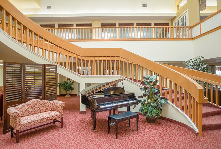 Elegant lobby with a grand piano and staircase.