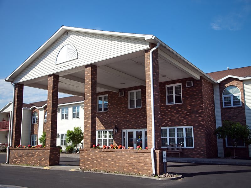 Brick building with a large covered entrance on a sunny day.