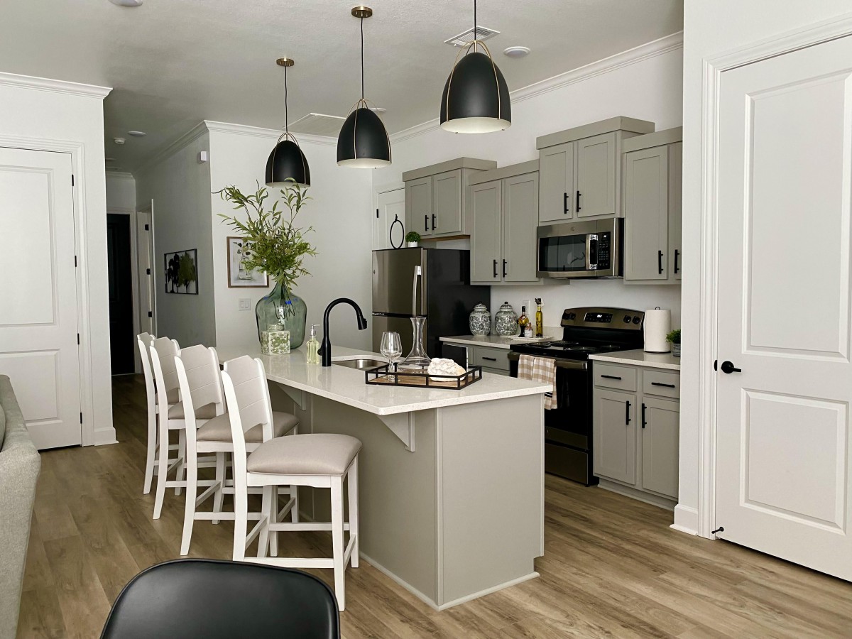 A modern kitchen featuring an island with bar stools, pendant lighting, and sleek cabinetry.