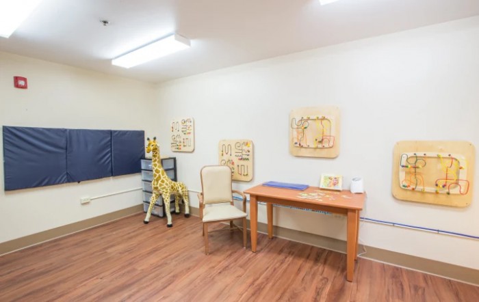 A cozy playroom with a table, chairs, and a large giraffe stuffed animal.