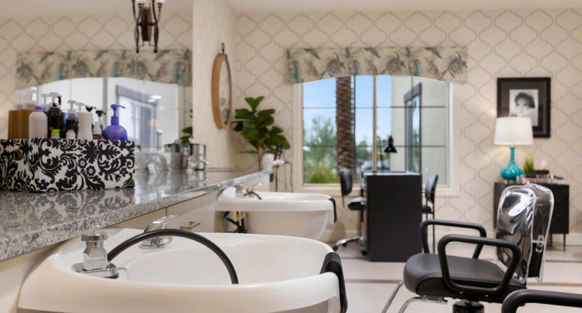 A modern and bright hair salon interior featuring styling chairs, sinks, and large mirrors.