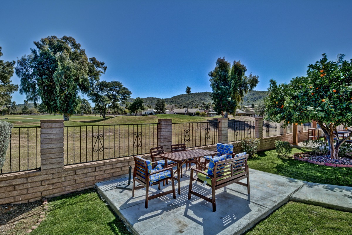 A scenic outdoor patio with a table and chairs overlooking a garden and trees.