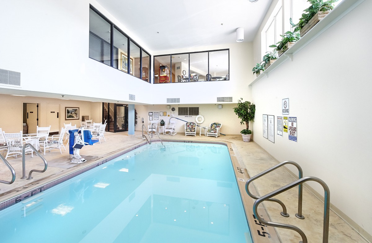 An inviting indoor swimming pool area with seating and a bright, spacious design.