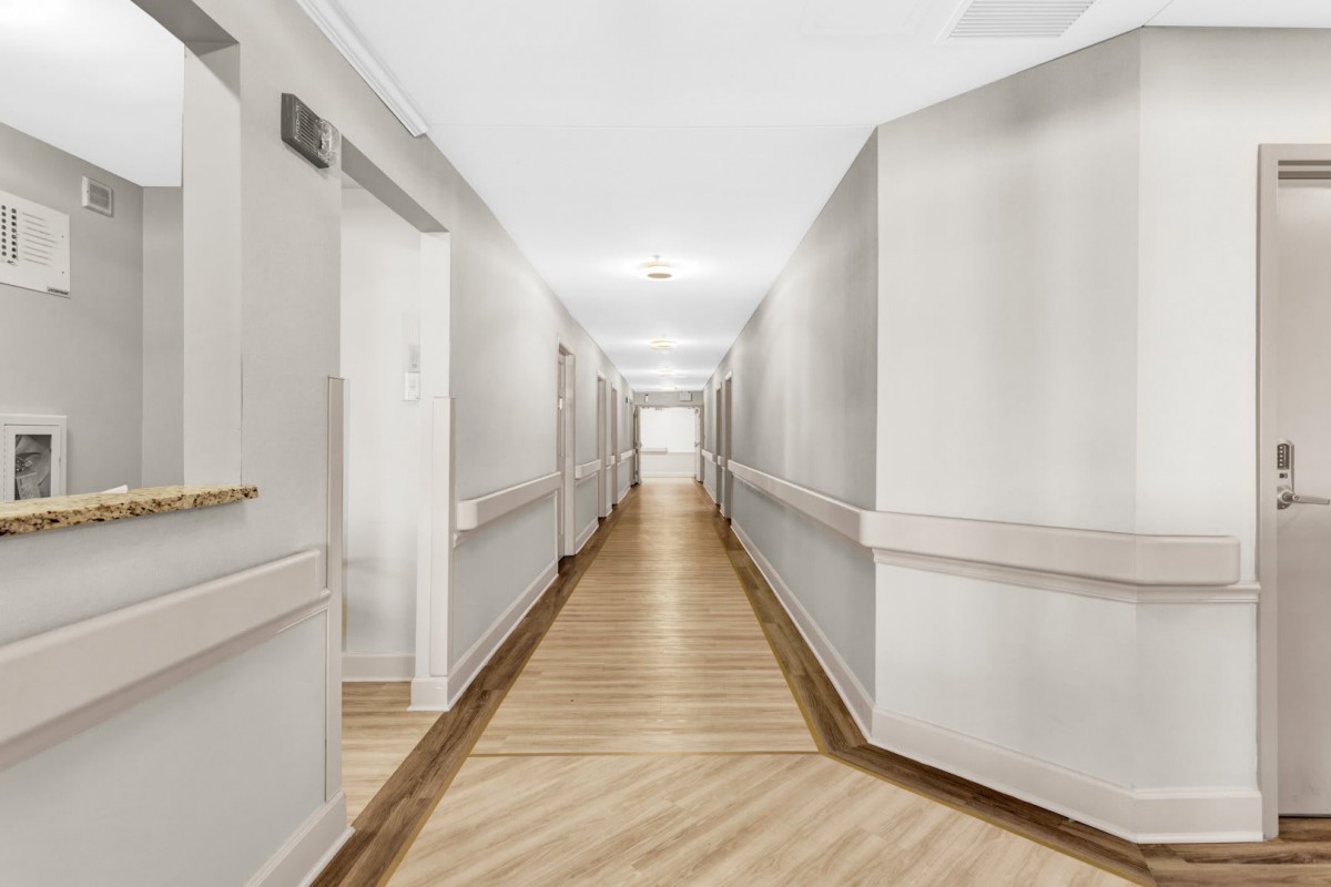 A bright, modern hallway with wooden flooring and clean, neutral-colored walls.
