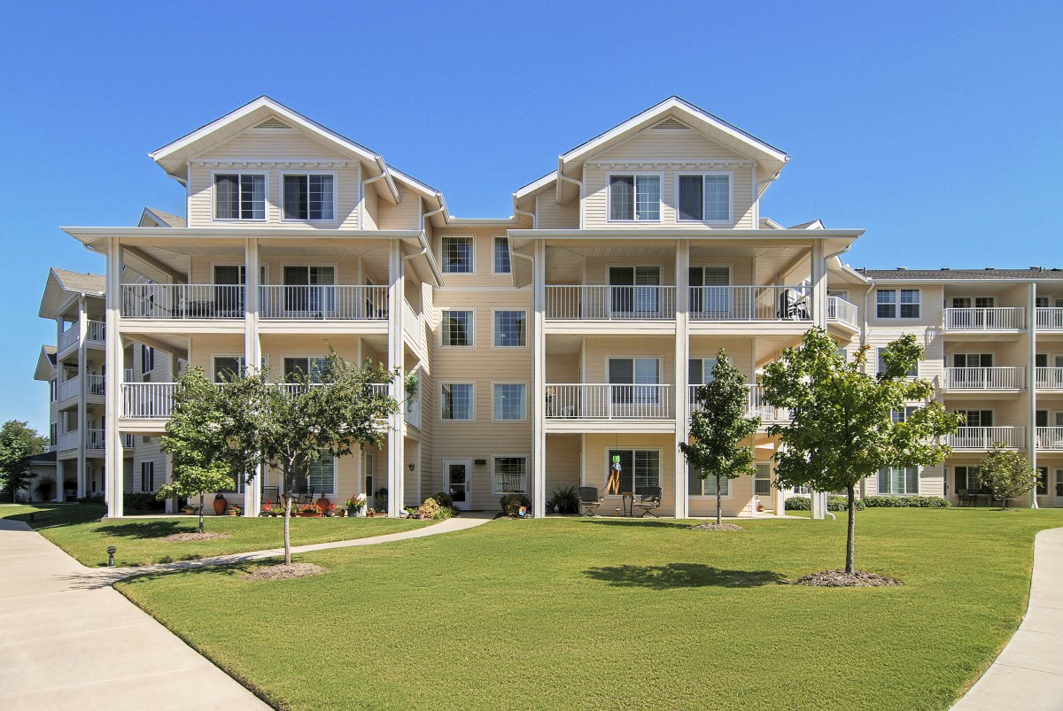 A modern apartment building with balconies and a spacious lawn area.