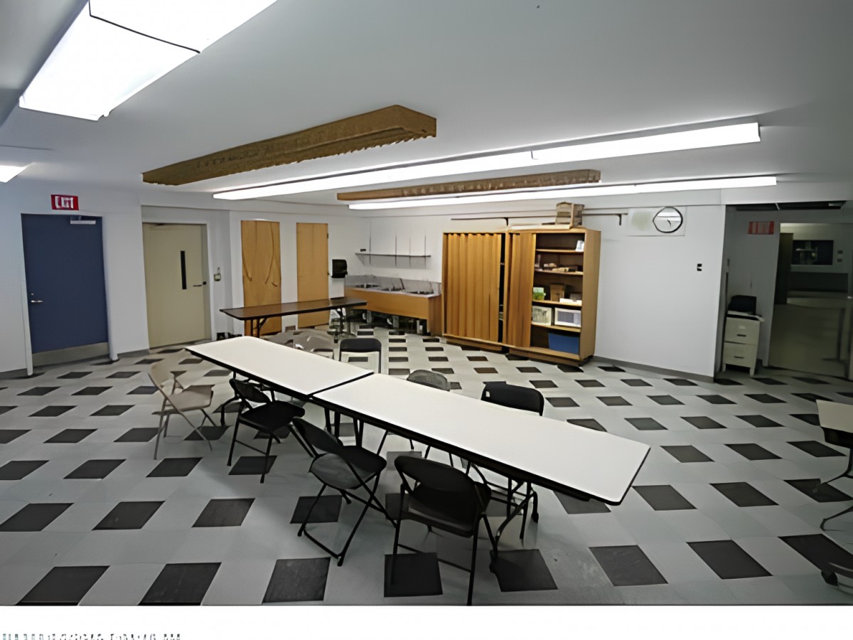 An empty classroom or meeting room with tables arranged in a U-shape and chairs around them.