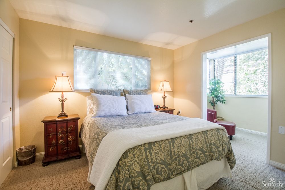 A cozy bedroom with a comfortable bed, two lamps, and window light.