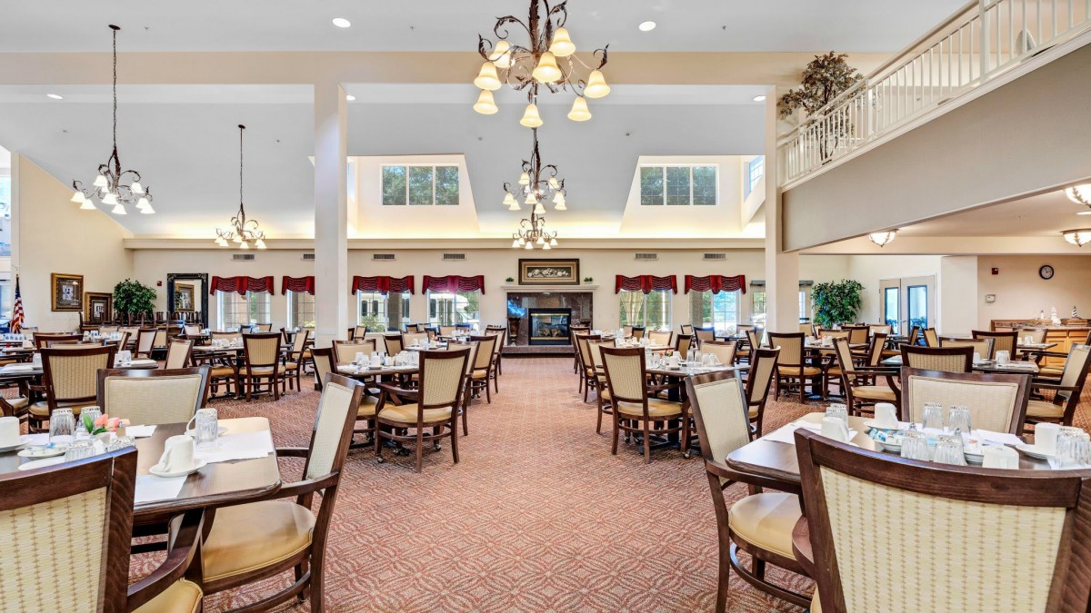 A spacious dining area with elegant chandeliers and neatly arranged tables and chairs.