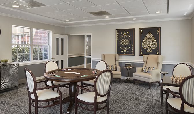 A stylish meeting room featuring a poker table, comfortable chairs, and decorative artwork on the walls.