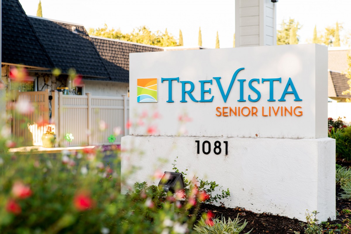 Entrance sign for Trevista Senior Living, featuring landscaping and outdoor setting.