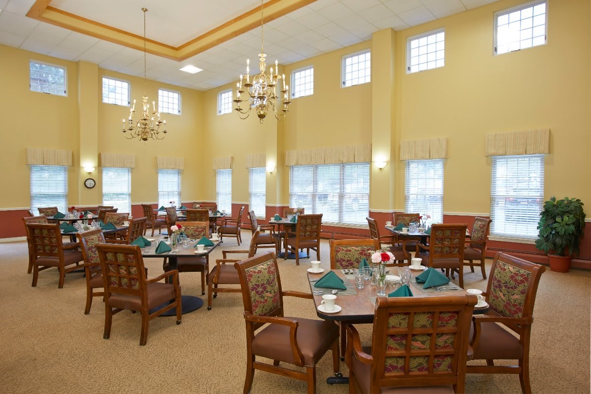 An elegant dining room with chandeliers and set tables ready for guests.