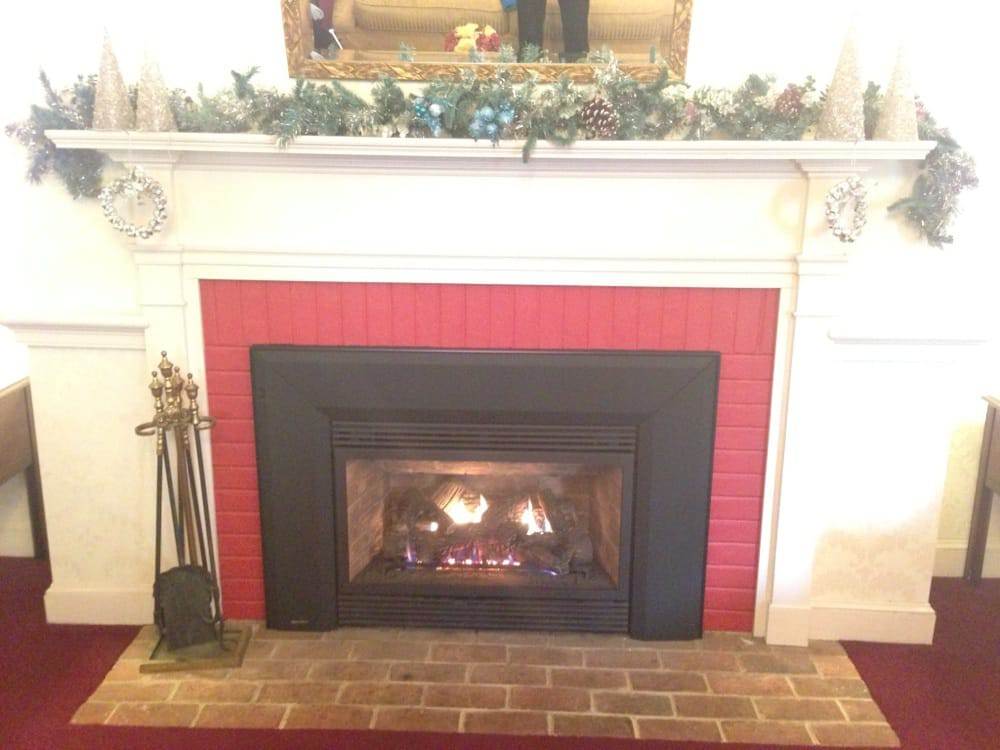 A cozy indoor fireplace with a decorative mantel and burning firewood.