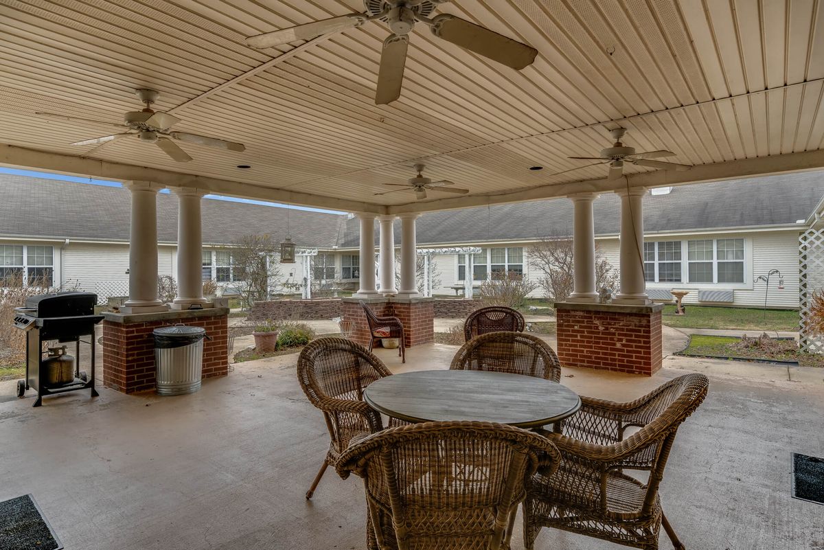 A spacious outdoor patio area with wicker furniture and ceiling fans, providing a comfortable relaxation space.