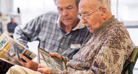 Two men engaged in conversation while looking through old photographs.