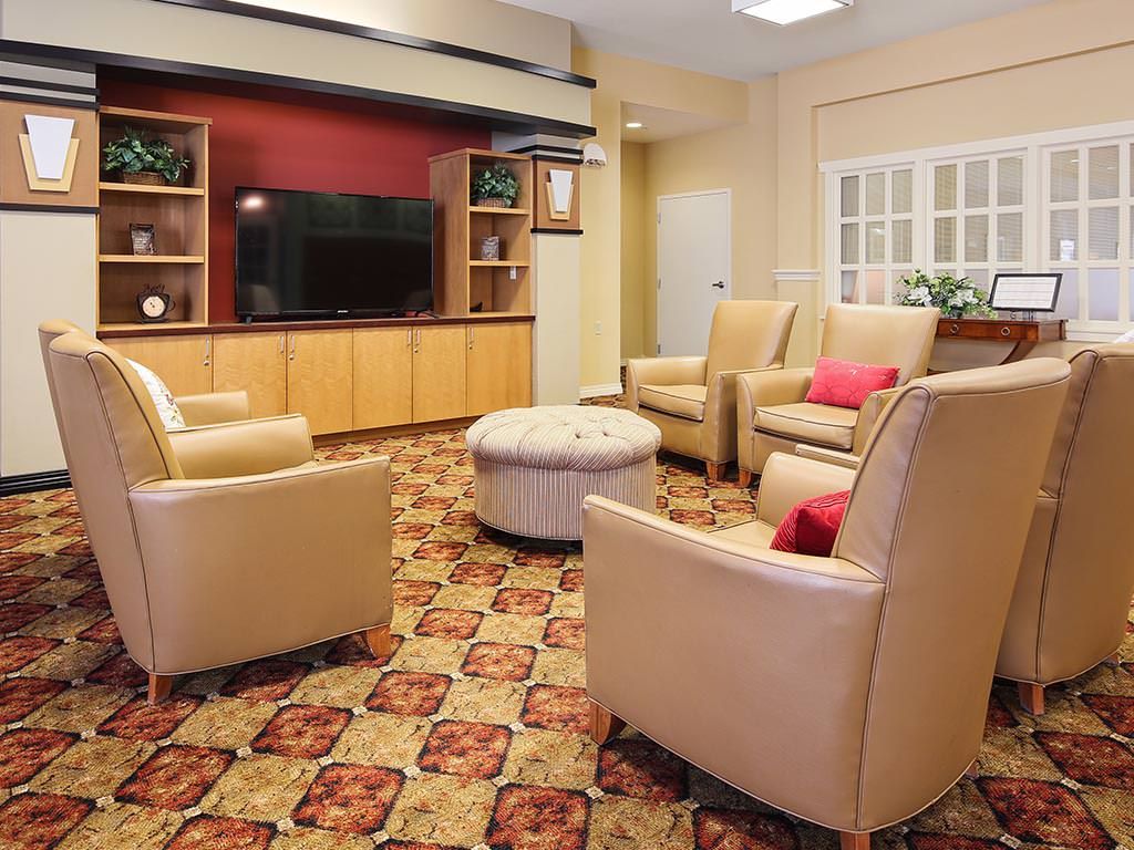 A cozy living room with armchairs, a television, and a patterned carpet.