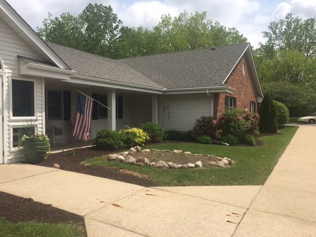A suburban house with a well-maintained lawn and garden, featuring a flag by the entrance.