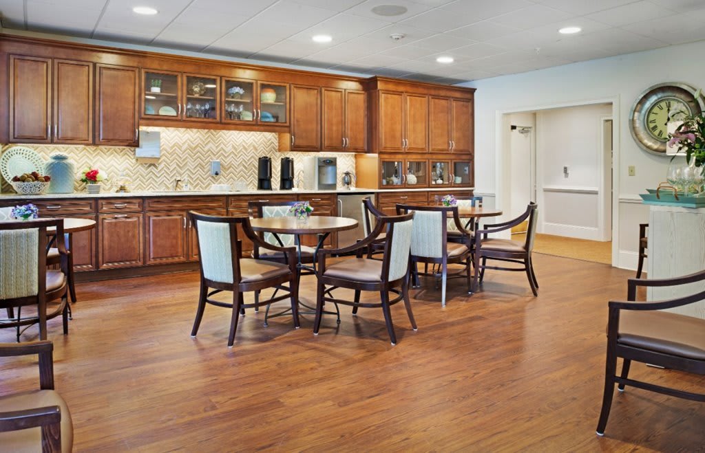 A modern kitchen and dining area featuring wooden cabinets, tables, and chairs on a hardwood floor.