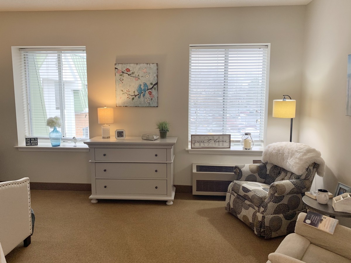 A cozy living room with a comfortable armchair, dresser, and soft lighting.