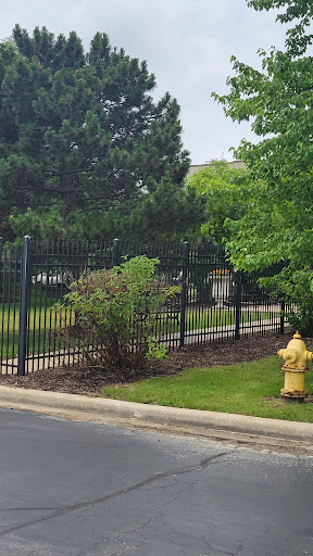 A view of a fenced area with a fire hydrant and surrounding greenery.