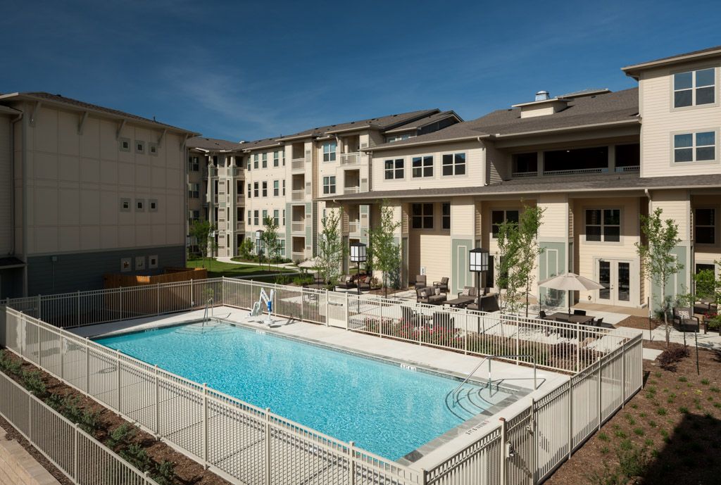 An apartment complex featuring an outdoor swimming pool with surrounding seating.