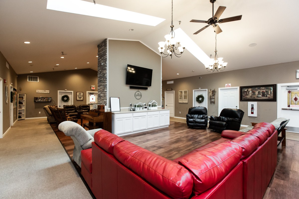 A modern living room with a red sofa, hardwood floors, and elegant chandeliers.