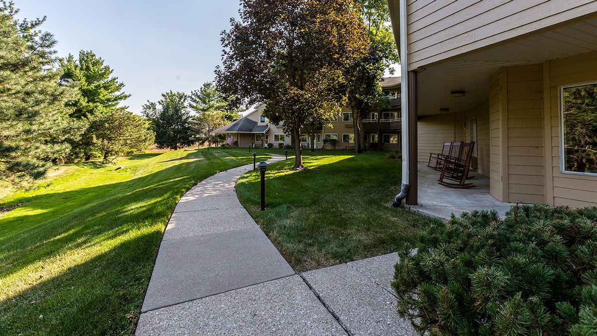 A serene pathway winding through an apartment complex with lush greenery and trees.