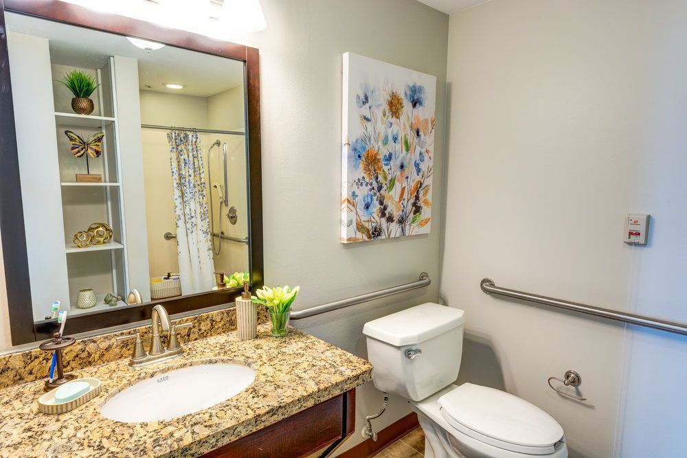 A modern bathroom with granite countertops, floral artwork, and a shower curtain.