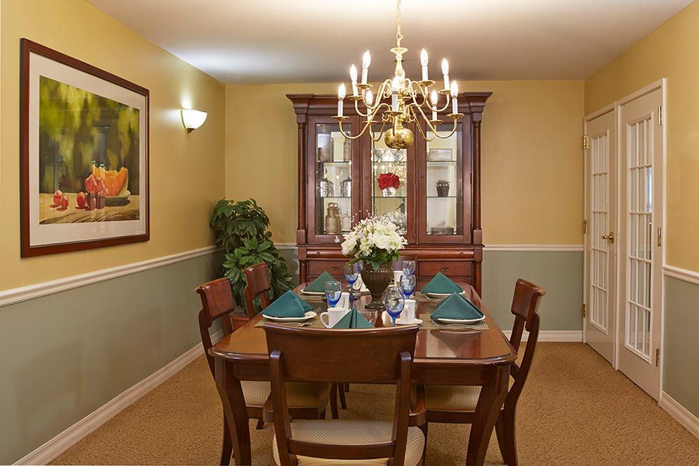 A traditional dining room with a wooden table and chairs, set under an elegant chandelier.
