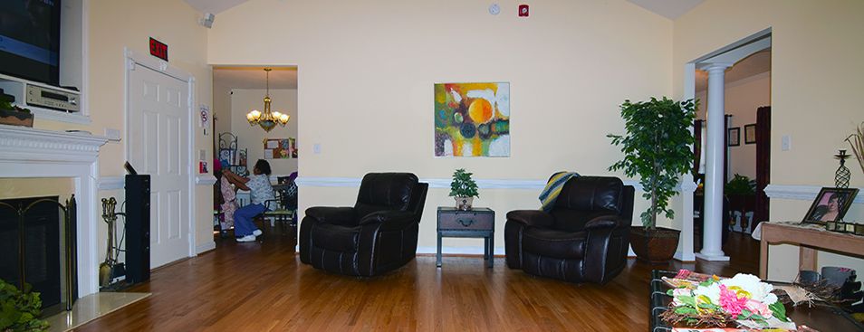 A cozy living room setup with two black chairs, a small table with a plant, and abstract artwork on the wall.
