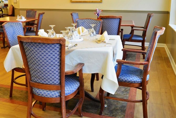 An elegantly set dining table with blue patterned chairs in a restaurant.