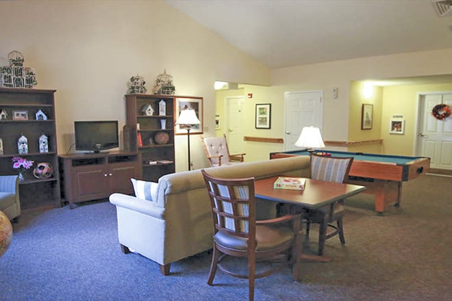 A cozy living room with a sofa, table, television, and bookshelf.