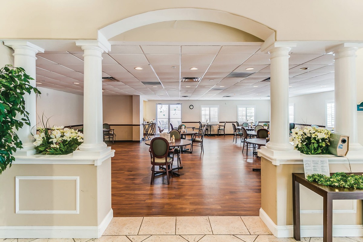 A spacious dining area with elegant columns and wooden flooring.